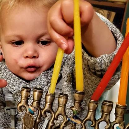 a toddler inserting candles into a menorah